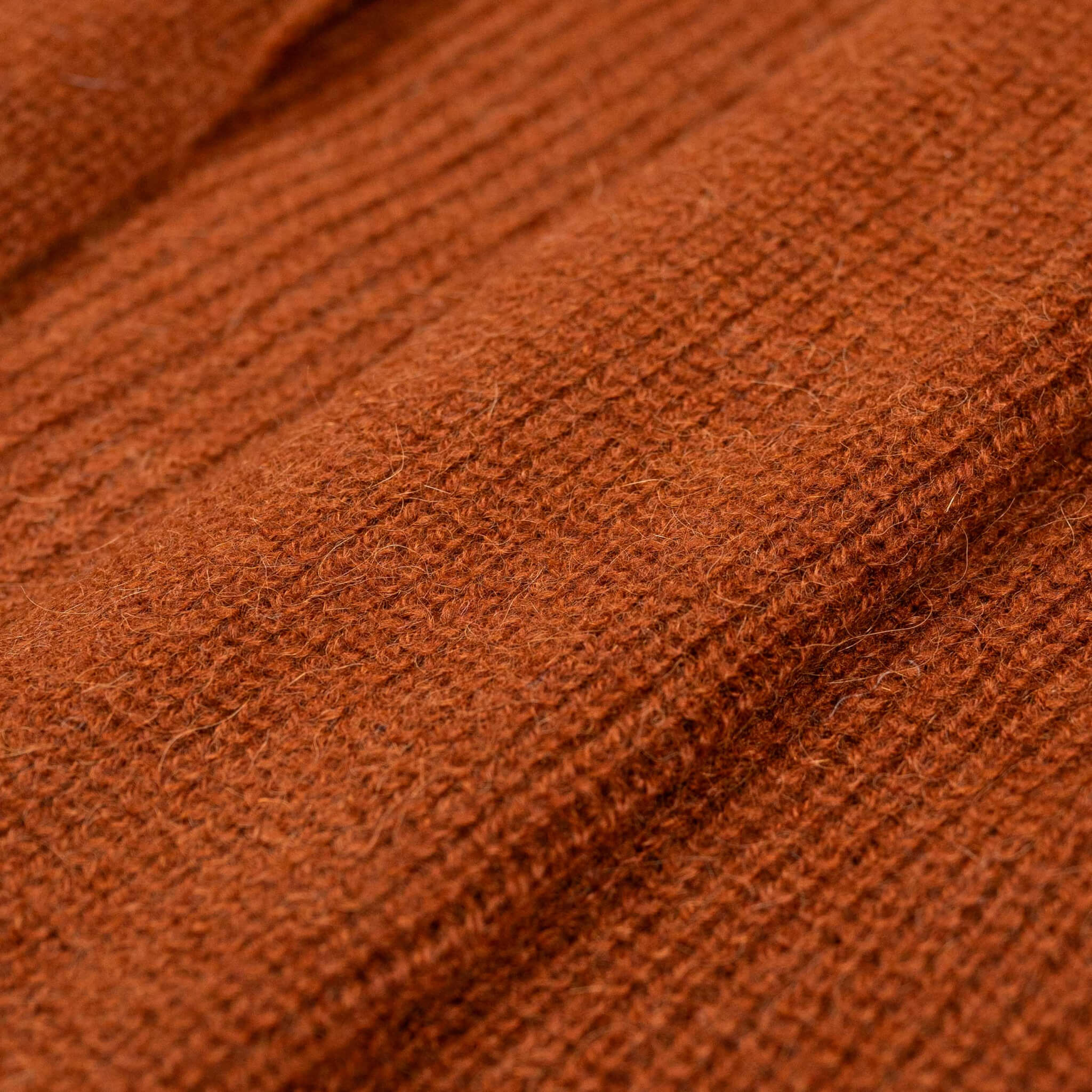 Nahaufnahme des feinen Textils des Alpaka Cardigans Mira in dunkelorange