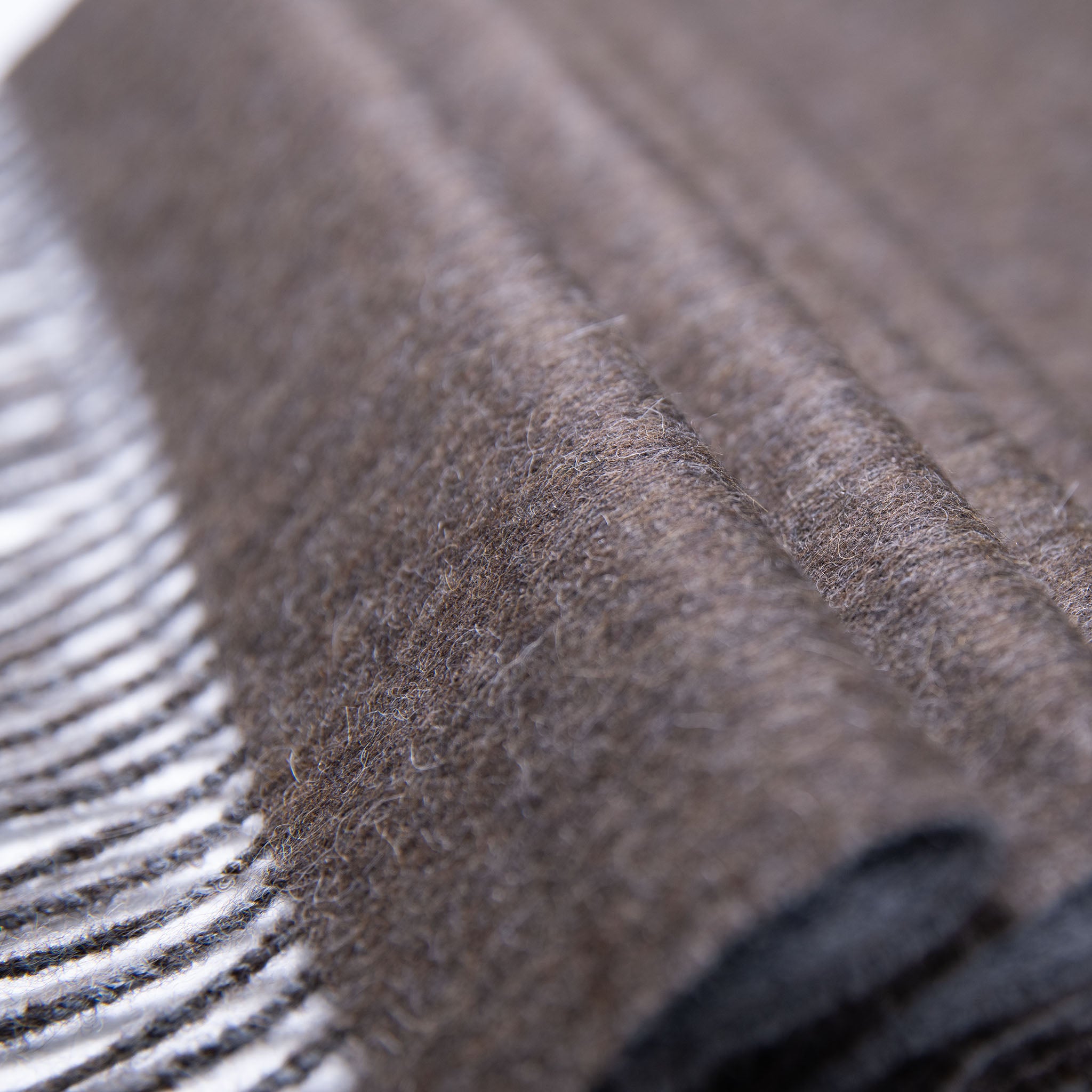 Nahaufnahme Textil des zweifarbigen Alpaka Schals in dunkelbraun mit Fransensaum