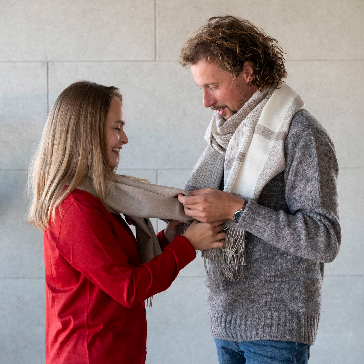 Mann und Frau stehen sich gegenüber und fühlen den Alpaka Schal des jeweils anderen