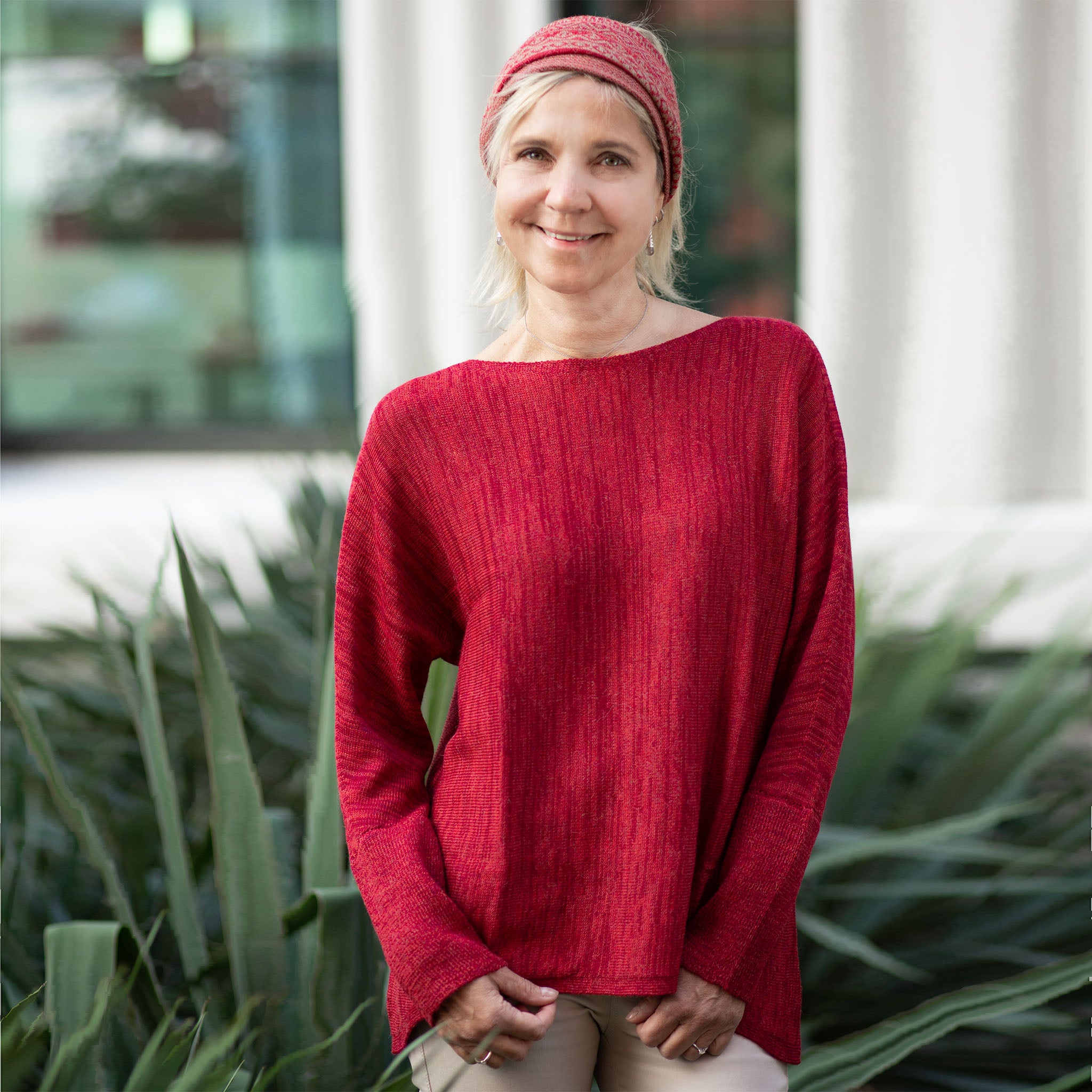 Blonde Frau trägt die sommerliche Tunika aus Alpakawolle in dunkelrot und genießt höchste Bewegungsfreiheit