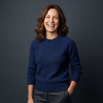 Attraktive Frau mit Locken trägt eleganten Alpaka Strickpullover in dunkelblau - aus 100% reiner Babyalpaka Wolle in Peru gefertigt