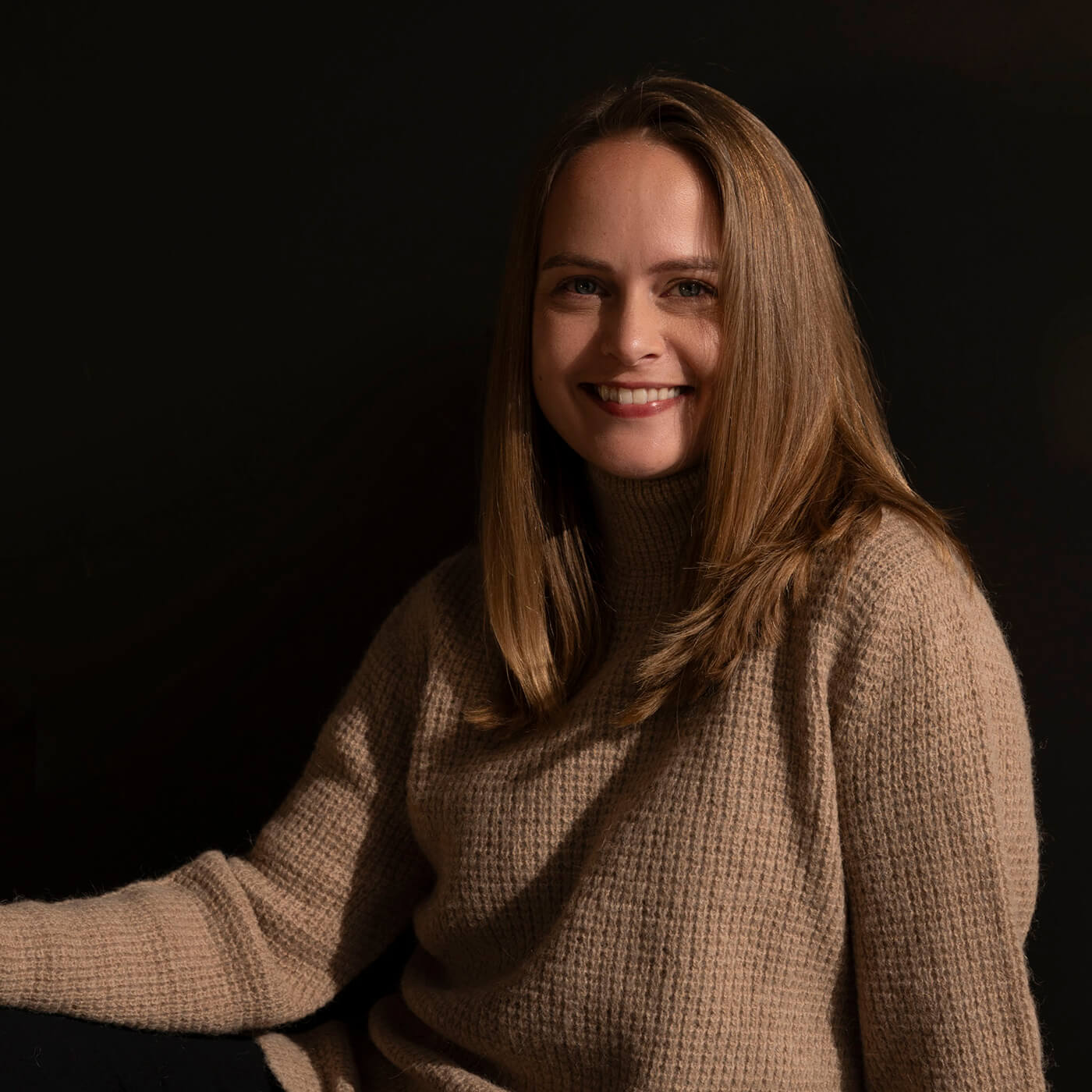 Dunkelblondes Model trägt den Nuna Alpaka Rollkragenpullover in hellbraun von Alpakin