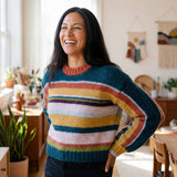 Dunkelhaarige Frau in ihrem Atelier trägt den farbenfrohen Cusi Alpaka Pullover - ideal für den Frühling