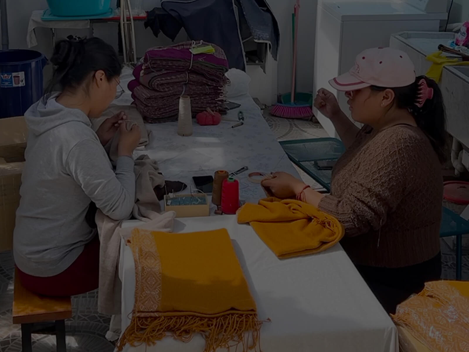 Zwei Frauen sitzen am Tisch und arbeiten am Flor Alpaka Poncho von Alpakin