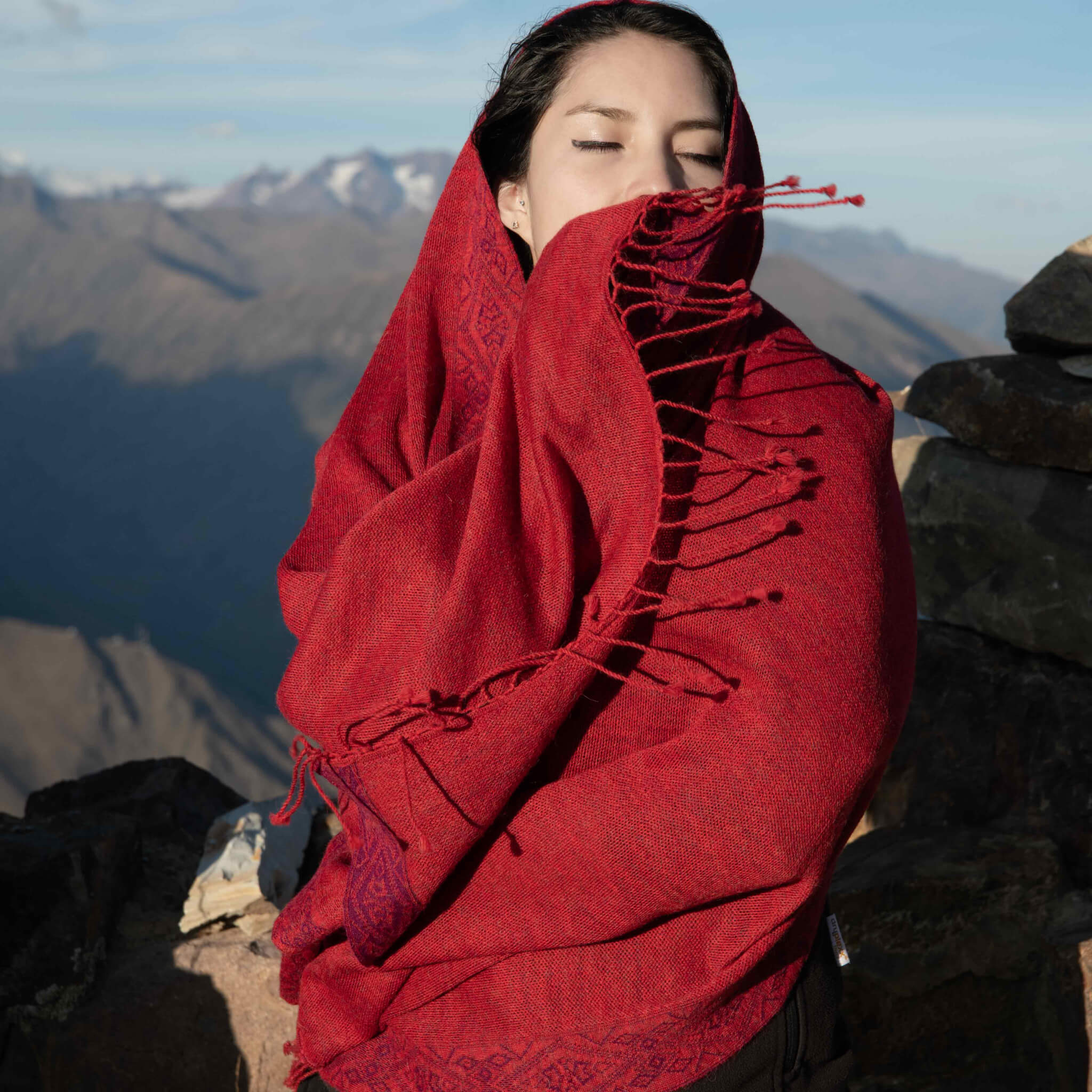 Model hüllt sich in FLOR Alpaka Poncho Schal für Damen von Alpakin in rot