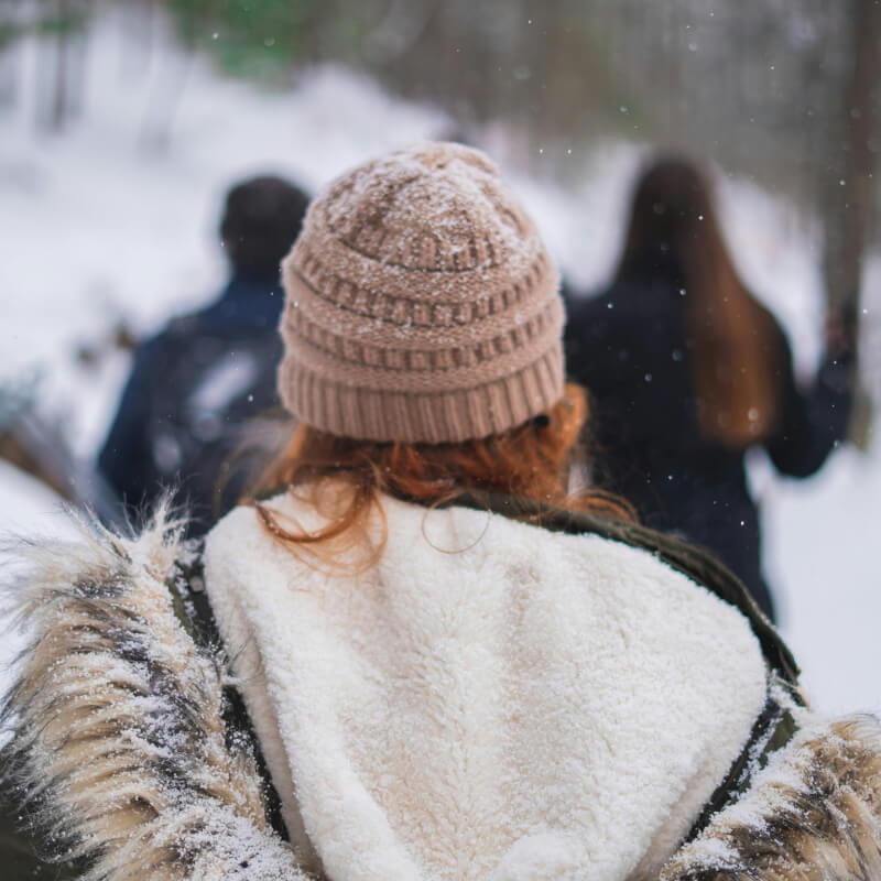 Frau mit Winterjacke und Mütze von hinten im Freien