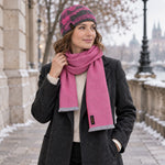 Frau trägt vor einer Stadtkulisse im Winter das Premium Set in pink, bestehend aus feinem Babyalpaka Schal und Merino Mütze mit Maulbeerseide für angenehme Wärme