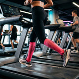 Frau trägt pinke Kompressionsstrümpfe auf dem Laufband