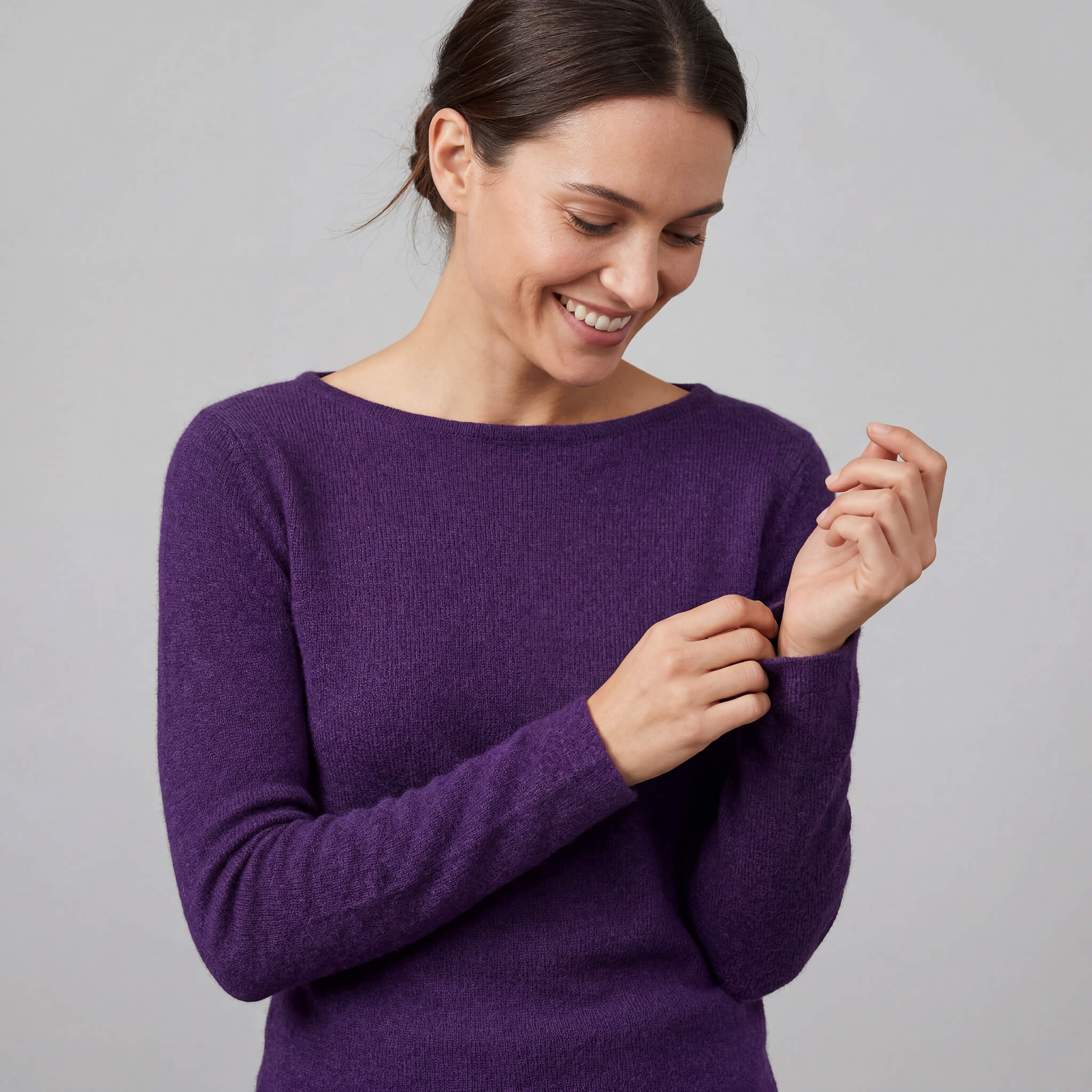 Frau fühlt die Weichheit ihres 100% reinen Babyalpaka Pullovers und lächelt dabei glücklich