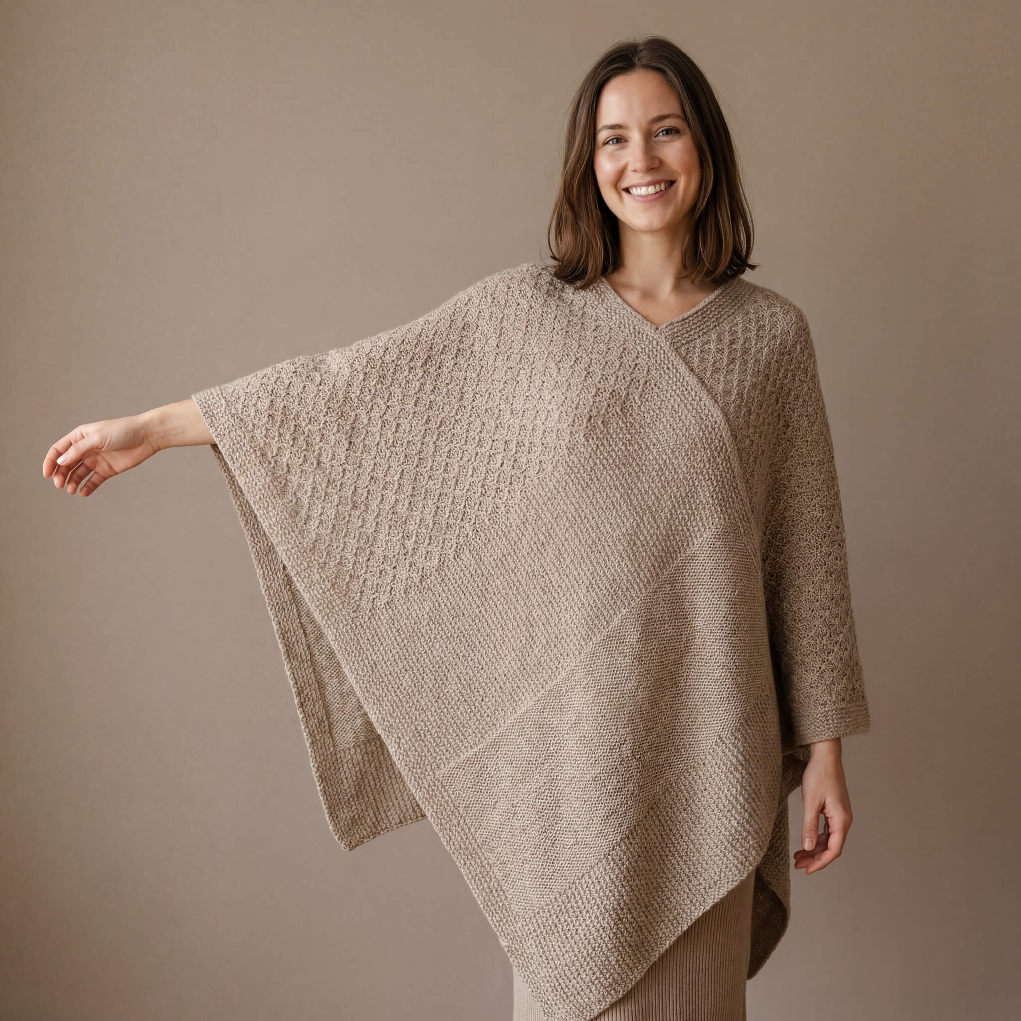 Junge Frau streckt den Arm ihres bequemen Alpaka Ponchos mit Strickmuster aus