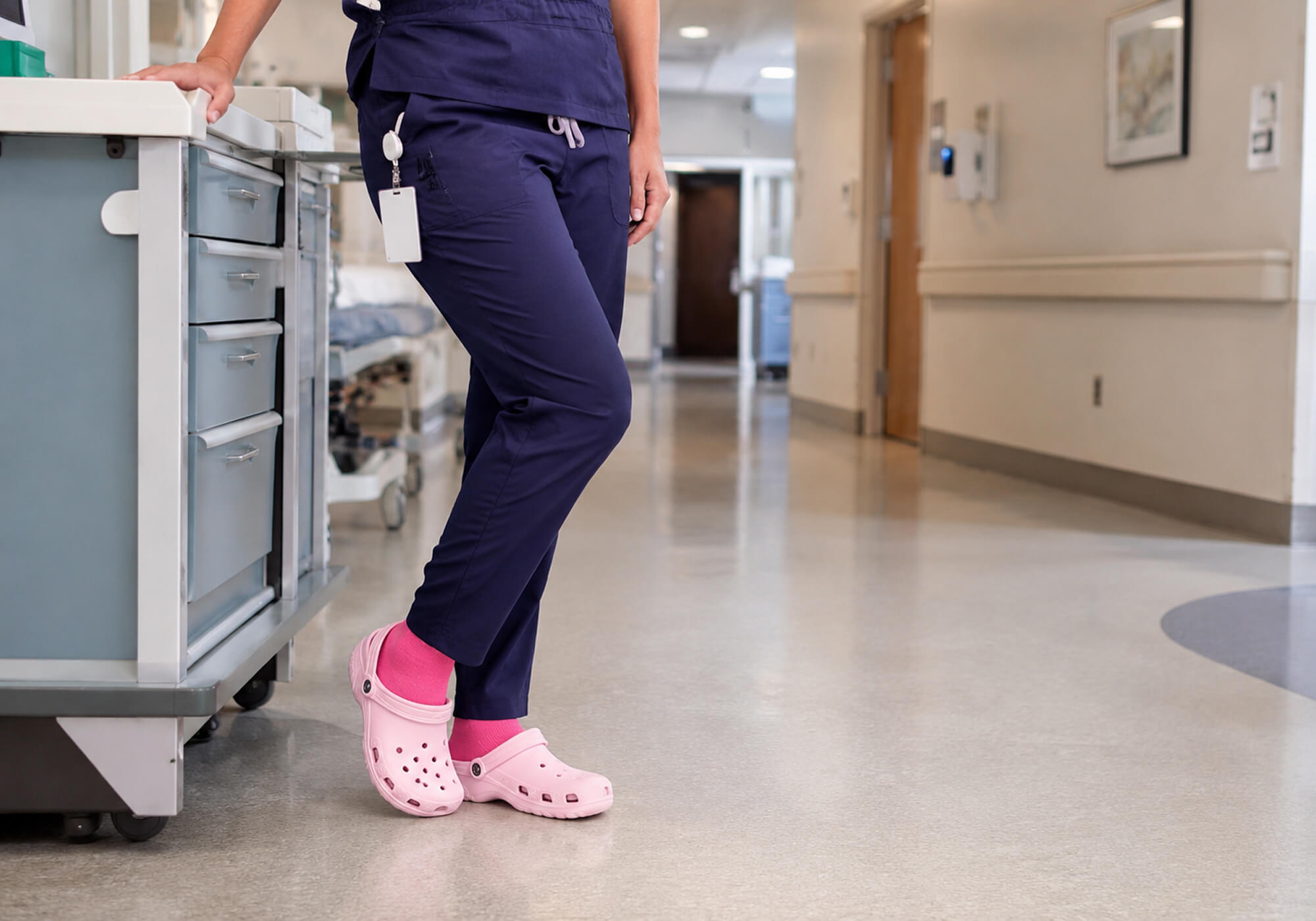 Pinke Kompressionsstrümpfe für lange Arbeitstage auf den Beinen einer Krankenschwester