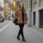 Frau schlendert mit ihrem eleganten Alpaka Poncho Mantel durch Frankfurt am Main