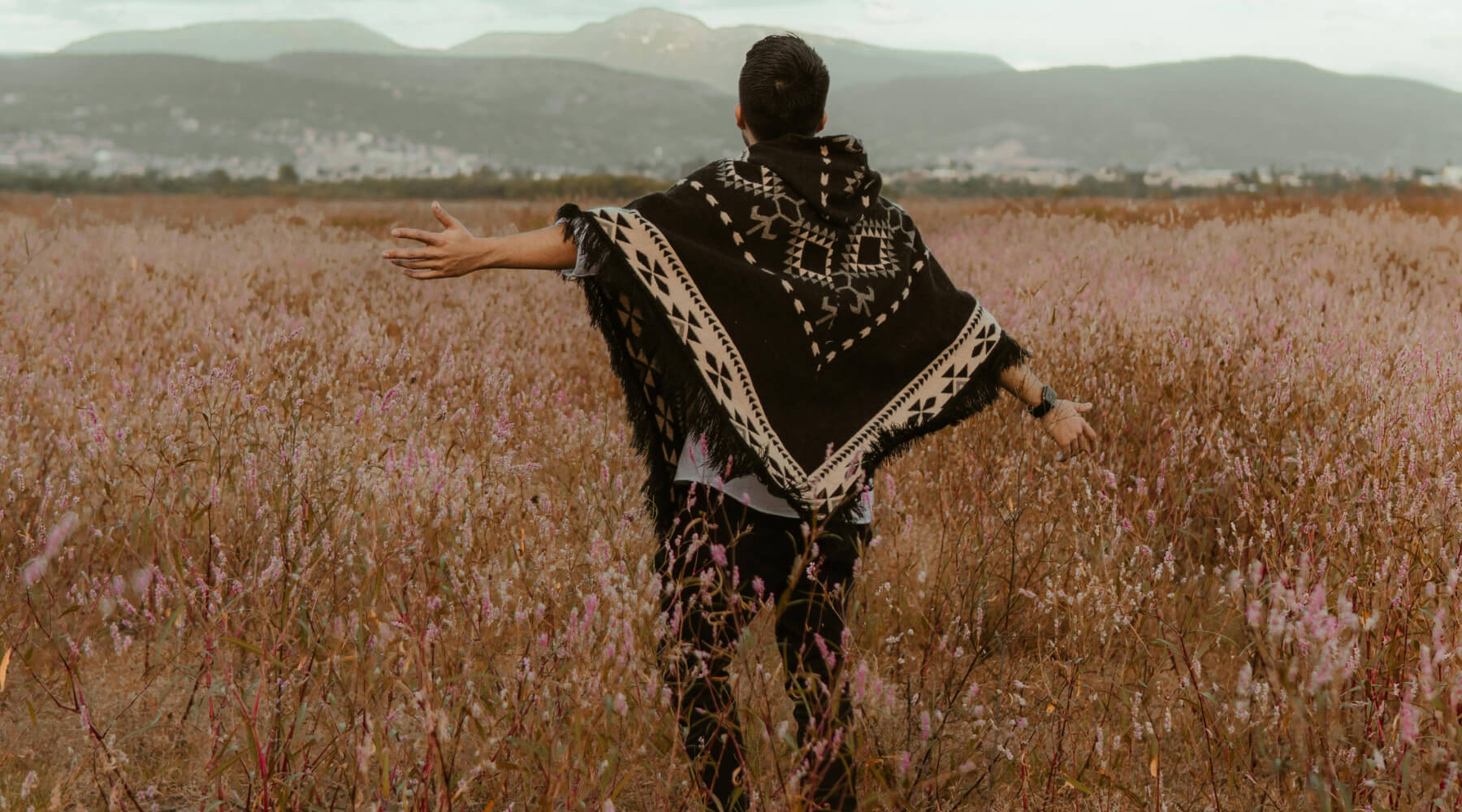 Mann von hinten trägt typisch-bunten peruanischen Poncho