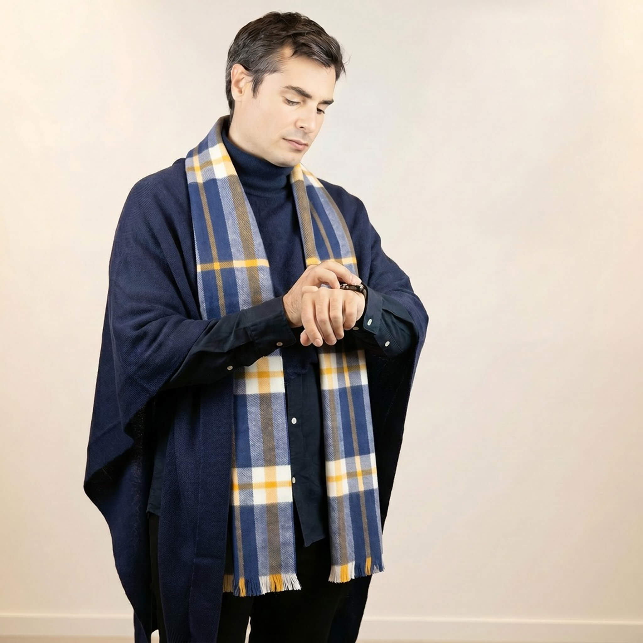 Das Alpakin British-Style Set: Mann trägt den Puma Herren Poncho mit Kragen in dunkellau in Kombination mit blauem Schottenkaro Schal.
