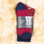 Dunkelrote Socken mit Alpaka Motiv auf kuscheligem Alpaka Fell gelegt